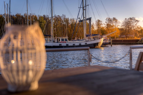 View from the houseboat in Peenemünde with a blurred lantern and sailing boat moored by the water.