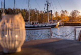 Vista dalla houseboat a Peenemünde con lanterna sfocata e barca a vela ormeggiata sull’acqua.