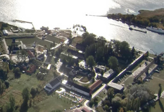 Vista aerea della houseboat a Peenemünde vicino al fiume, con edifici e aree verdi circostanti.