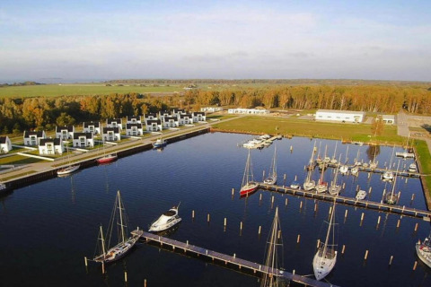 Vue aérienne d’une marina avec maisons modernes et voiliers à Peenemünde, entourée de verdure.