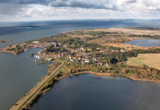 Luchtfoto vanaf Houseboat in Peenemünde met water, dorpshuizen en omringende natuur op de achtergrond.