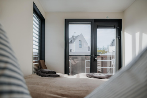 Interior view from Houseboat in Peenemünde with large windows, a double bed, and folded towels.
