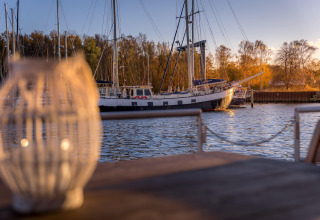 Vista da una houseboat a Peenemünde con una barca a vela sul molo e lanterna sfocata in primo piano.