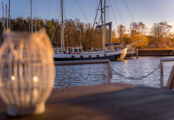 Vista da una houseboat a Peenemünde con una barca a vela sul molo e lanterna sfocata in primo piano.