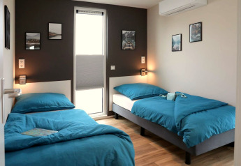 Moderne slaapkamer met twee eenpersoonsbedden, blauwe lakens en muurdecoratie op een woonboot in Ribnitz-Damgarten, Duitsland.