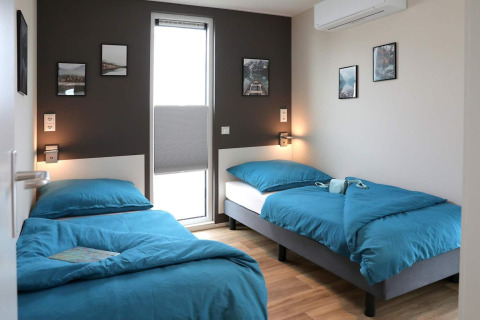 Camera moderna con due letti singoli, biancheria da letto blu e quadri murali su una houseboat a Ribnitz-Damgarten, Germania.