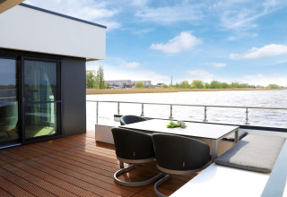 Moderne terrasse med udsigt til vandet på husbåd i Ribnitz-Damgarten, Tyskland, med havemøbler.