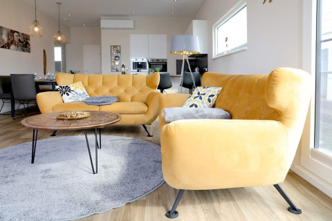 Lyst og moderne stue på husbåd i Ribnitz-Damgarten, Tyskland med gule sofaer og stort vindue.