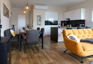 Sala y cocina moderna en una casa flotante en Ribnitz-Damgarten, Alemania, con sofá amarillo.