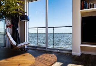 Living area on a houseboat in Ribnitz-Damgarten, Germany, featuring a water view through large windows.