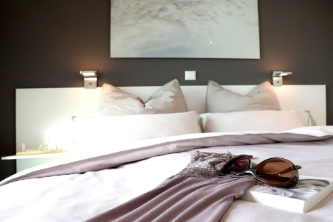 Cama moderna con cojines, gafas de sol y libro en Houseboat «in Ribnitz-Damgarten», Alemania, decoración acogedora