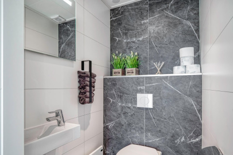 Bagno moderno su una casa galleggiante a Ribnitz-Damgarten, Germania, con piastrelle grigie e decor minimal.