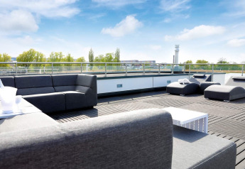 Moderne tagterrasse på husbåd i Ribnitz-Damgarten, Tyskland med komfortable grå sofaer og lounge.