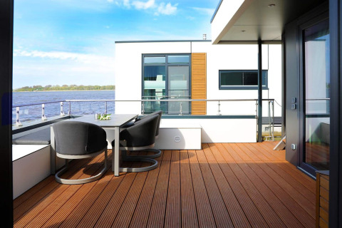 Modern houseboat terrace with dining set and water view at Houseboat in Ribnitz-Damgarten, Germany.