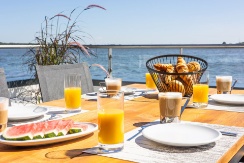 Ontbijt op het dek van een woonboot met sap, koffie, watermeloen en gebak bij het water in Duitsland.