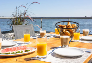 Desayuno al aire libre en una casa flotante con jugo, café, sandía y bollería junto al agua en Alemania.