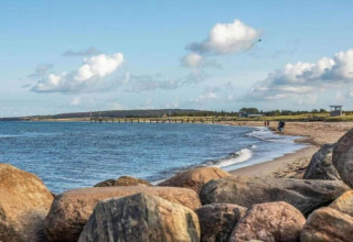 Vue de la plage et de la mer depuis Houseboat à Ribnitz-Damgarten, avec des rochers au premier plan.