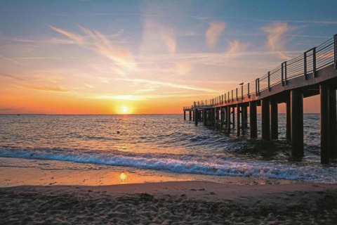 Stunning sunset view from the beach with a pier near Houseboat in Ribnitz-Damgarten, gentle waves rolling in.