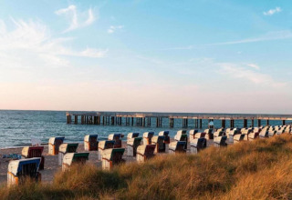 Beach scene with rows of beach chairs and a pier extending into the sea, near Houseboat in Ribnitz-Damgarten.