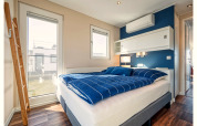 Lichte, moderne slaapkamer op een woonboot in Ribnitz-Damgarten met blauwe dekens en veel licht.