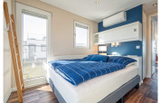Dormitorio moderno y luminoso en una casa flotante en Ribnitz-Damgarten con ropa de cama azul.