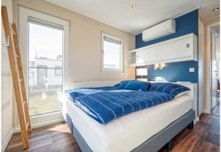 Bright, modern bedroom on a houseboat in Ribnitz-Damgarten with blue bedding and ample sunlight.