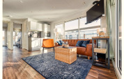 Lichte, moderne woonkamer op een woonboot in Ribnitz-Damgarten met leren bank, tv en open keuken.