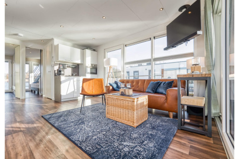 Bright, modern living room on a houseboat in Ribnitz-Damgarten with leather sofa, large windows and kitchen.