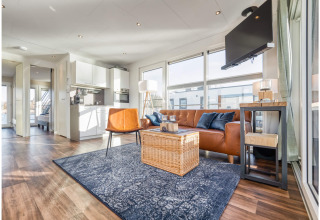 Moderne, lichte woonkamer op een woonboot in Ribnitz-Damgarten met leren zetel, tv en open keuken.
