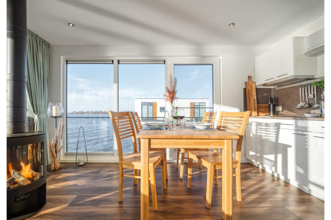 Dining area in a houseboat in Ribnitz-Damgarten, featuring modern decor, a fireplace, and water views.