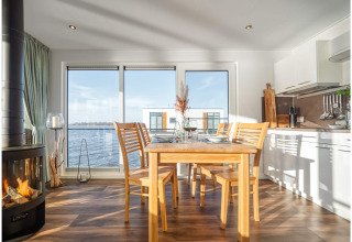 Dining area in a houseboat in Ribnitz-Damgarten, featuring modern decor, a fireplace, and water views.
