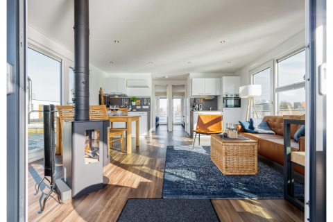 Modern houseboat in Ribnitz-Damgarten featuring a cozy living area, wood stove, dining space, and large windows.