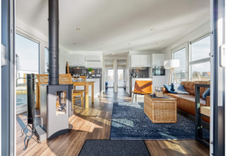 Modern houseboat in Ribnitz-Damgarten featuring a cozy living area, wood stove, dining space, and large windows.
