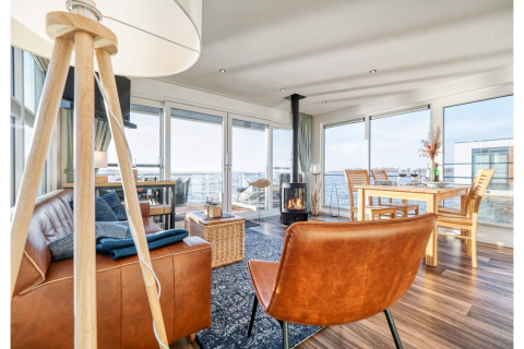 Stylish living room on a houseboat in Ribnitz-Damgarten with leather furniture and scenic water views.