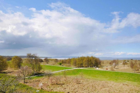 Vue sur la campagne près de Ribnitz-Damgarten depuis un houseboat en Allemagne, sous un ciel partiellement nuageux.