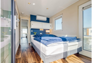 Modern bedroom on a houseboat in Ribnitz-Damgarten featuring blue bedding, wood flooring and views to the water.