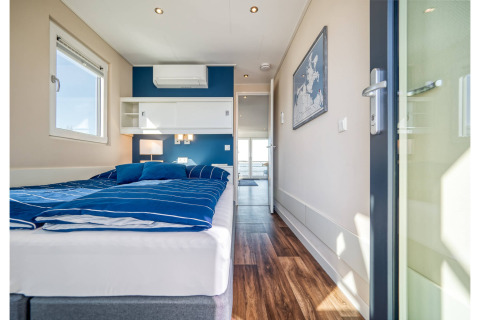 Modern bedroom with blue accents on a houseboat in Ribnitz-Damgarten, featuring a double bed and wood floor.