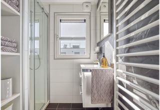 Modern bathroom on a houseboat in Ribnitz-Damgarten with shower, sink, towels and large window.