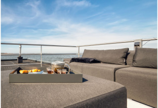 Modern lounge seating and tray with tea and snacks on a houseboat deck in Ribnitz-Damgarten, Germany.