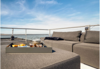 Salon confortable et plateau avec thé et en-cas sur une péniche à Ribnitz-Damgarten sous ciel bleu.