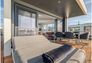 Terrasse moderne sur une péniche à Ribnitz-Damgarten, Allemagne, avec transat, table et fauteuils confortables.