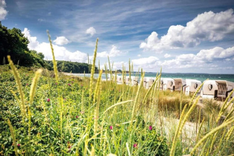 Scenic view from a houseboat in Ribnitz-Damgarten, Germany, with dunes, beach chairs, and sea in sight.