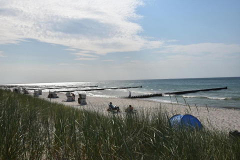 Udsigt over en sandstrand ved havet med klitter, strandstole og mennesker, fotograferet fra Houseboat i Ribnitz-Damgarten.