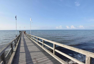 Immagine di un lungo molo di legno con bandiere, che si estende verso il mare calmo a Ribnitz-Damgarten.