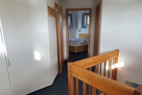 Innenaufnahme eines Hausboots mit Holztreppengeländer, Schlafzimmer und modernen Holztüren.