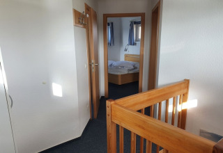 Innenaufnahme eines Hausboots mit Holztreppengeländer, Schlafzimmer und modernen Holztüren.