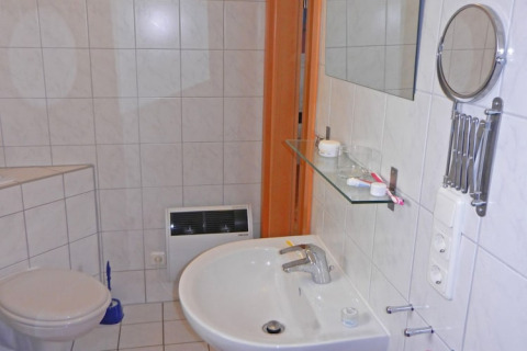 Bathroom on a houseboat showing a sink, mirror, shelf, toilet, and wall-mounted electric heater.