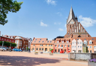 Bunte Häuser und eine große Kirche am Marktplatz unter blauem Himmel in einer deutschen Stadt.