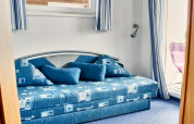 Blauwe slaapkamer met moderne sofa en grote kussens op een woonboot in Duitsland.