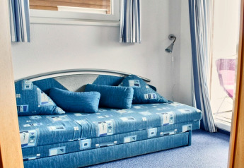 Blauwe slaapkamer met moderne sofa en grote kussens op een woonboot in Duitsland.